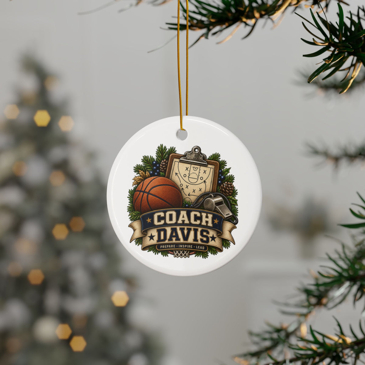 A round white Christmas ornament hanging from a gold string on a Christmas tree branch. The ornament features a custom sports graphic with a basketball, clipboard, pinecones, and a banner reading 'COACH DAVIS'.